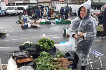 Una vendedora se protege de la lluvia en la feria de Paiosaco